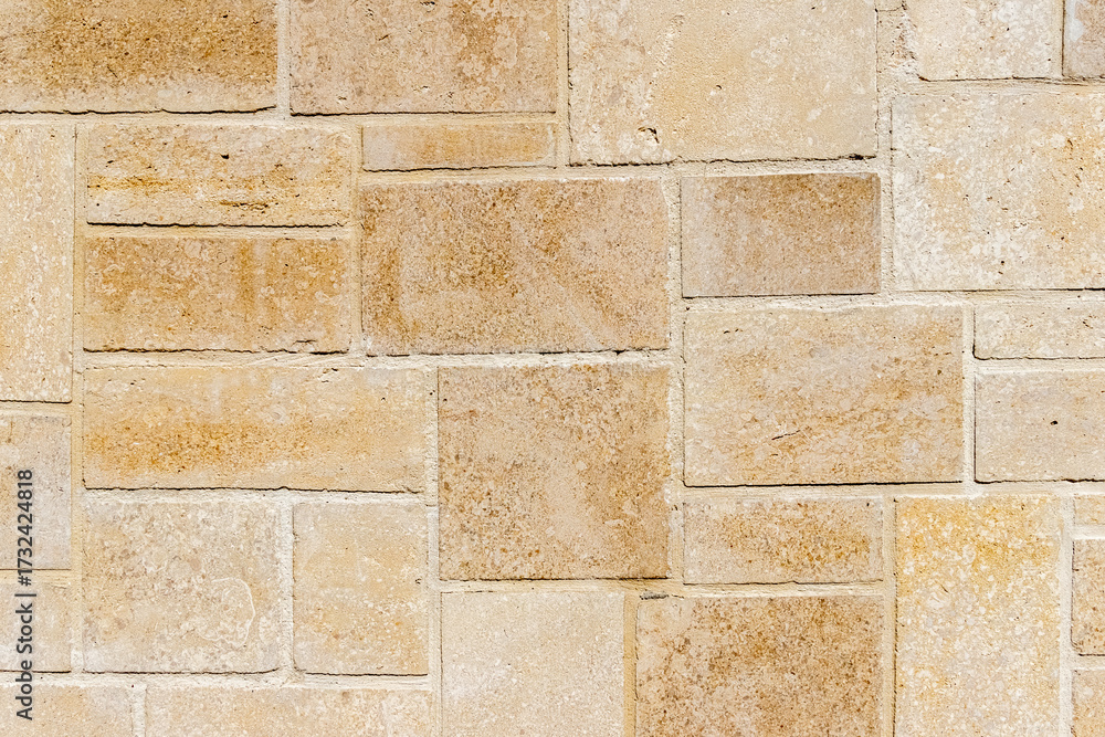 Naklejka premium Travertine, natural stone tiles, perfect for a background, creating a unique and aesthetic pattern of yellowish-beige rectangles of various sizes