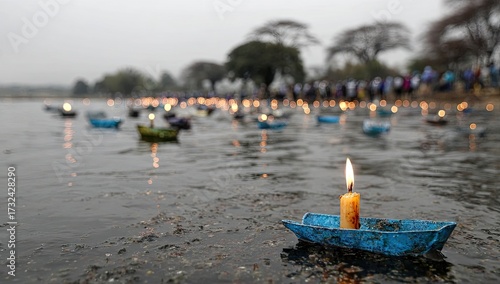 A small, paper boat carrying a candle floats on a lake, surrounded by many more, in a serene, reflective scene.
