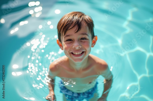 A cheerful boy smiles while standing in a crystal-clear pool, sunlight sparkling on the water surface. He enjoys a sunny summer day, creating joyful memories