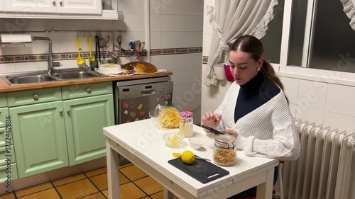 Teen girl sitting at the kitchen table eating snacks while talking on the phone