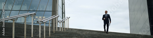 Cuadro en lienzo Header of middle aged Caucasian man walking down outdoor steps holding coffee cu