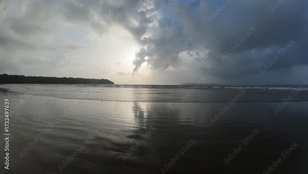 Obraz premium Serene Coastal Sunset with Cloud Reflections on Wet Sand Beach