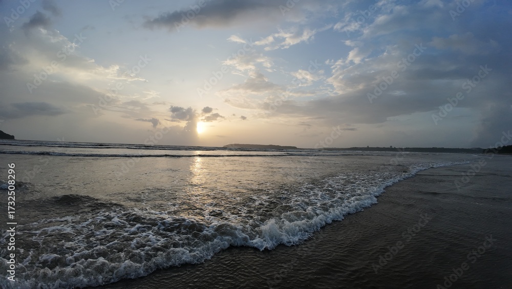 Obraz premium Idyllic Coastal Sunrise with Gentle Waves, Dramatic Clouds, and Mirror-Like Reflections