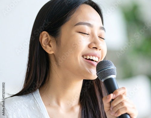 Primer plano de mujer joven cantando con un micrófono en casa, ojos cerrados y sonrisa amplia, fondo cálido y desenfocado, estilo fotográfico realista.
