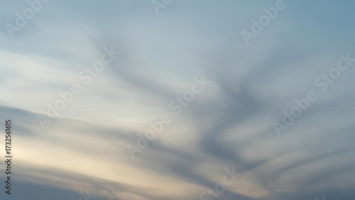 Wispy Clouds Streaking Across a Soft Blue Sky at Sunset.