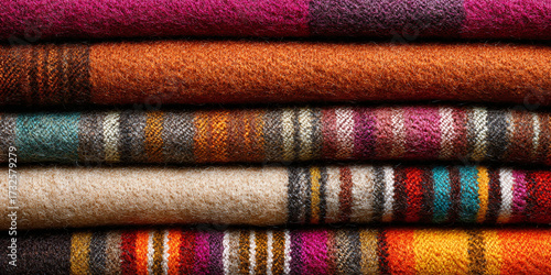 Stack of colorful wool blankets in red, orange and brown tones arranged together forming handmade textile background with cozy natural fibers - AI generated