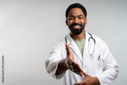 African young doctor smiling and shaking hands with patient in clinic, confident healthcare professional interaction