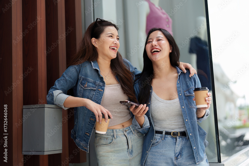 Naklejka premium Joyful Connection. Two young women laughing and enjoying coffee together.