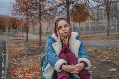 Foto A woman sitting pensively on a bench in a park surrounded by trees during autumn