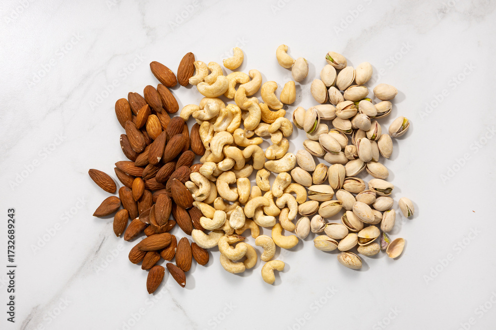 Fototapeta premium Overhead view of almond pistachio cashew nuts on light surface