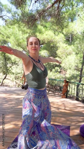 Woman practicing yoga pose outdoors on wooden deck under a tree	
