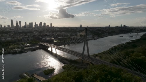Aerial drone view of Świętokrzyski Bridge in Warsaw at sunset with sun glare and city skyline, Poland
