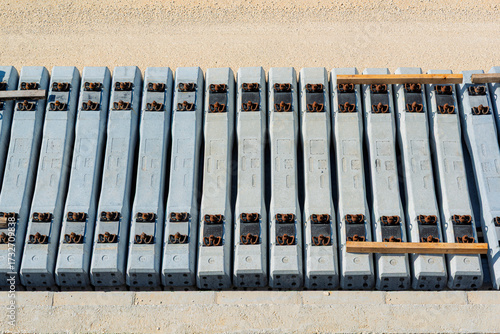 High-angle, detailed pattern of new reinforced concrete railway sleepers (railroad ties) neatly stacked in a construction site, ready for infrastructure development.