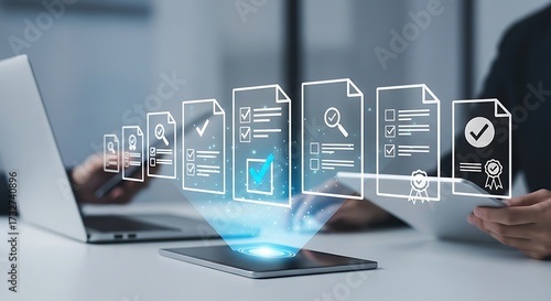 Person reviewing digital documents and certificates on a tablet with a laptop in the background