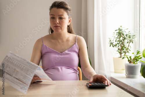 pregnant woman with calculator, computer pays utility bill. Receiving maternity benefits, social payments, maternity capital, donation. pregnancy and childbirth concept. calculate child's birth date