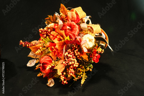 Front view, medium distance of, a cornucopia of colorful, dried flowers and ribbons with a black background