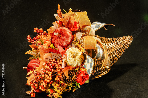 Side view, medium distance of, a cornucopia of, colorful, dried flowers and ribbons with a black background