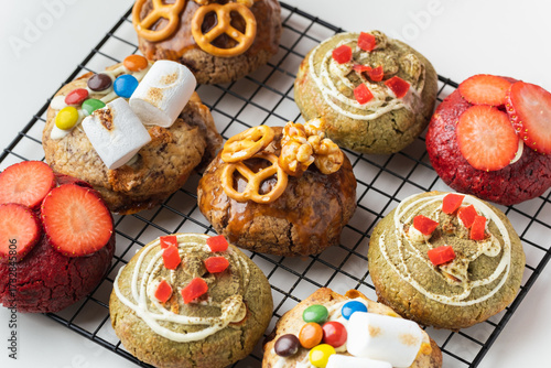Assortment of fresh chocolate American chip cookies with salted camel, caramel popcorn, matcha tea , marshmallow and colorful candies on white background. Different cookies on cooling rack