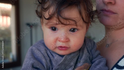 Close-up of baby resting on mother’s shoulder with visible runny nose while being comforted in caring and protective family home environment