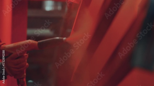 Professional painter in a workshop applying red powder coat paint to a metal structure with a spray gun, an industrial electrostatic process for finishing and surface protection