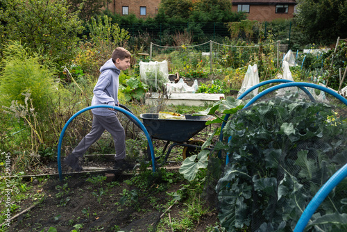 Boy Pushing Wheelbarrow in Community Garden