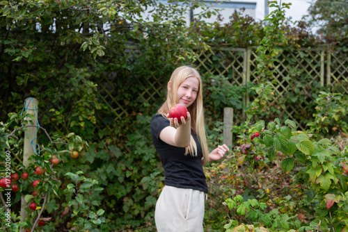 Young Person Offering Apple in Autumn Garden