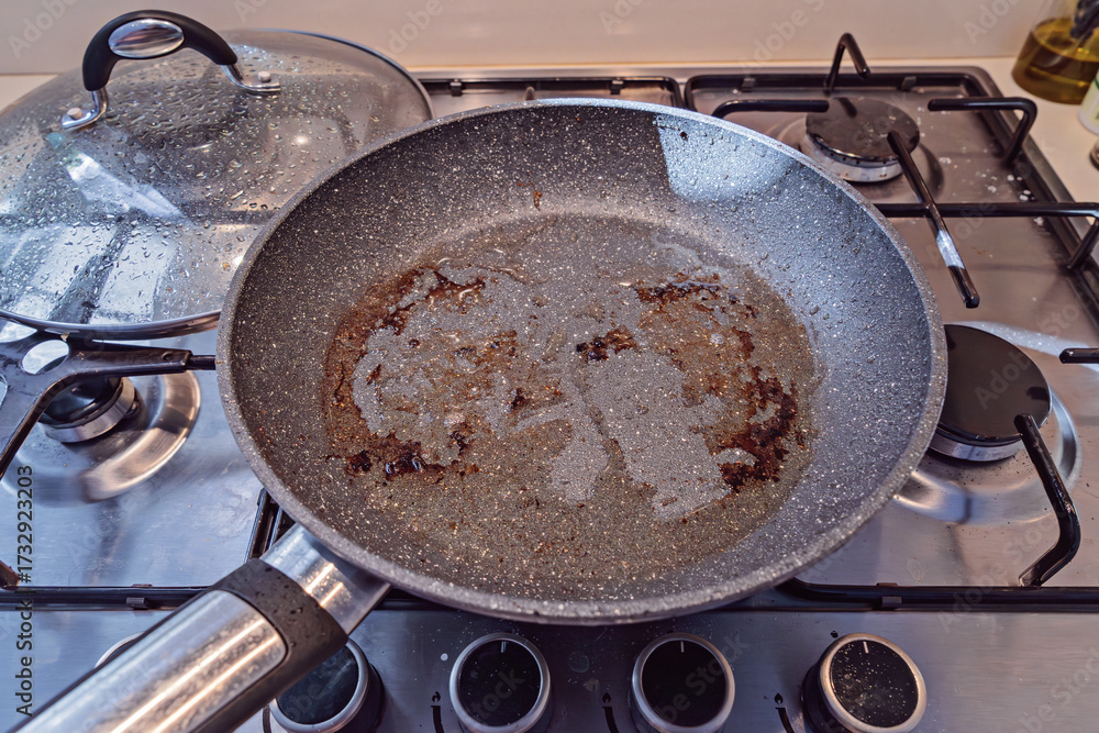 custom made wallpaper toronto digitalNonstick pan with burnt oil residue on gas burners, glass lid and utensils around, post cooking scene waiting for cleaning
