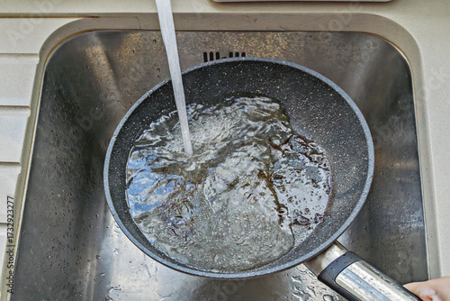 Wallpaper Mural Hot nonstick pan under tap with water stream and foam, burnt bits washing away, active rinsing step of cleaning Torontodigital.ca