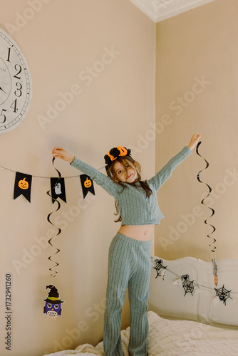 Little girl with hanging Halloween decor in the room.
