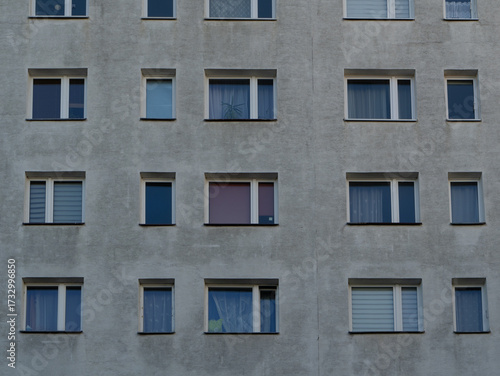 Concrete facade of an apartment block with repetitive windows, reflecting urban housing patterns and minimalist city architecture