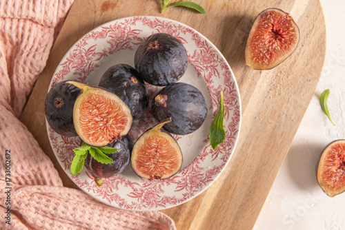 Wallpaper Mural A rustic top-down view of a plate of fresh figs, a wooden board, fresh stevia leaves, and a pink napkin in soft light Torontodigital.ca