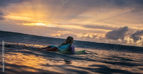 Surfing Girl in sunset sea waiting for the right wave