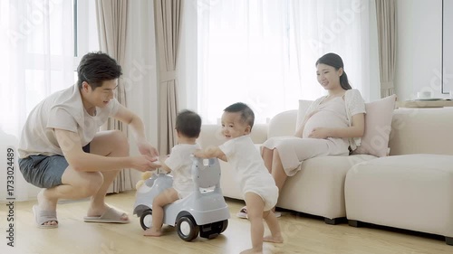 Parents watching their twin babies play with a baby vehicle
