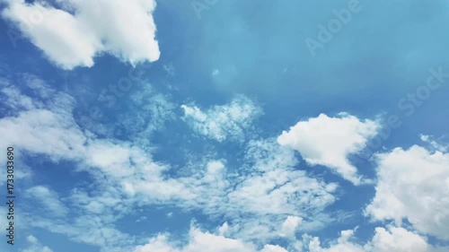 Dynamic sky with fluffy white clouds against a vivid blue backdrop, emphasizing natural beauty and airy atmosphere.Time-lapse video.