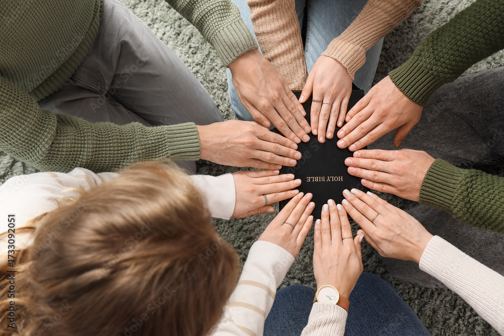 Obraz premium Group of people praying with Holy Bible on carpet, top view