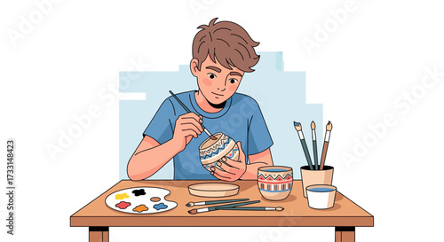 Young artist painting a ceramic mug at a wooden table.
