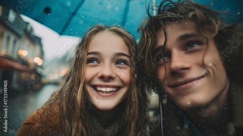 Smiling teens sharing umbrella in rainy weather