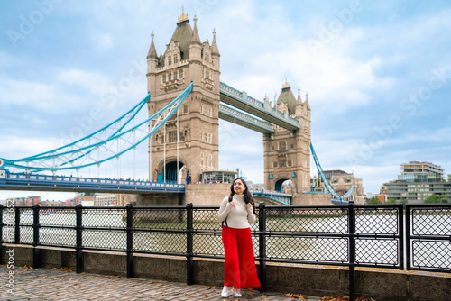 Photography Young happy Latina woman stands along the Thames in front of the iconic Tower Bridge in London, England