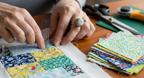 Close-up of hands arranging colorful fabric patches on a table with sewing tools and materials.