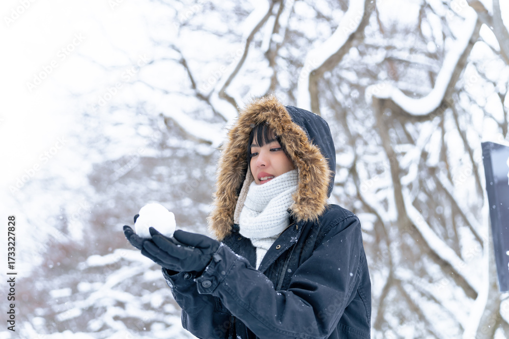 Obraz premium Young Asian woman traveler enjoy outdoor lifestyle travel nature forest mountain in winter snow season on holiday vacation. Attractive girl holding snowball with looking beautiful nature in snow day.