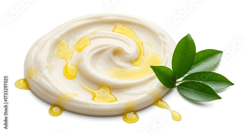 Swirl of creamy substance with drizzled oil and green leaves on white background