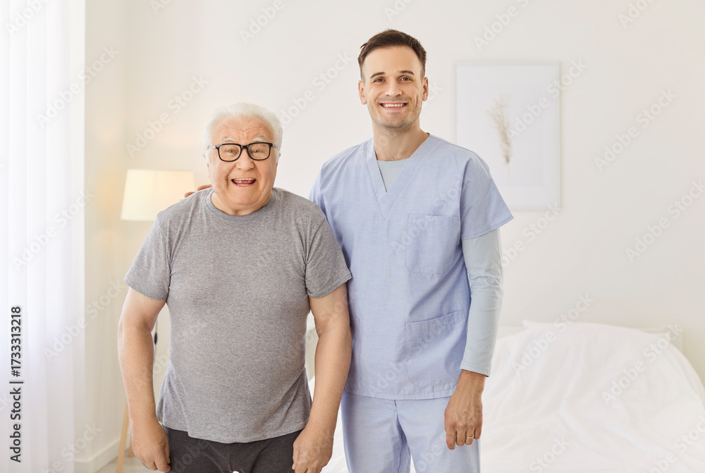 Obraz premium Portrait of happy health care worker with elderly man smiling and hugging in rehabilitation clinic. Young nurse with senior patient looking cheerful at camera. Nursing service and support concept.