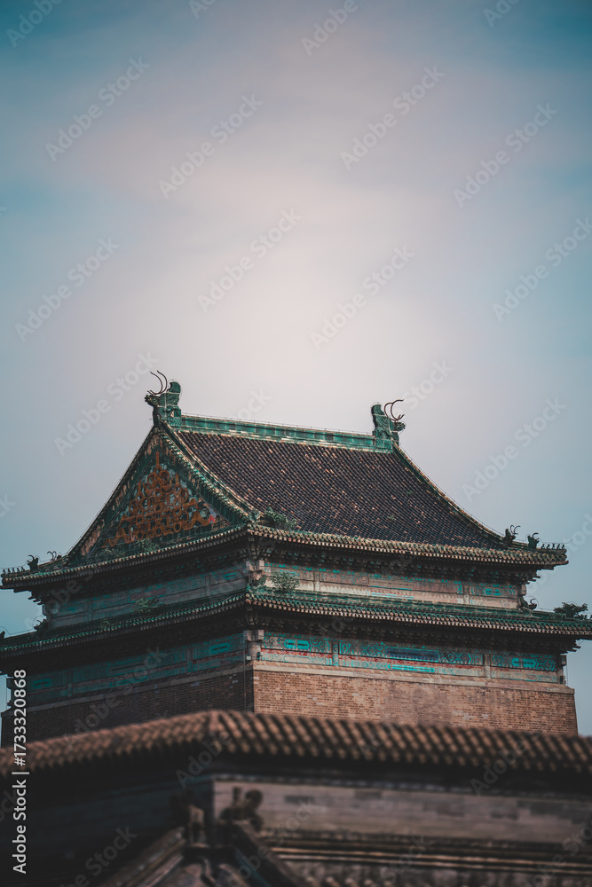 Fototapeta premium A grayscale snapshot reveals a weathered, old Beijing building with symmetrical architectural details lining a narrow, paved street, hinting at a historic urban scene.