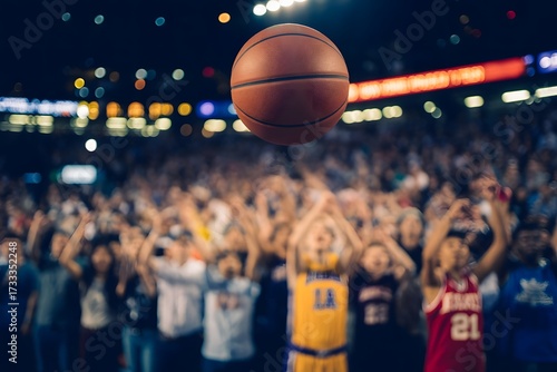 Excited young basketball players in colorful jerseys reach up towards a hovering basketball during a thrilling game with a cheering crowd in the background