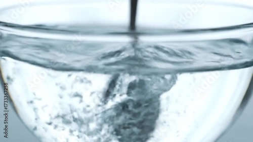 Wallpaper Mural Clear liquid being stirred in a glass, creating bubbles and ripples. Torontodigital.ca