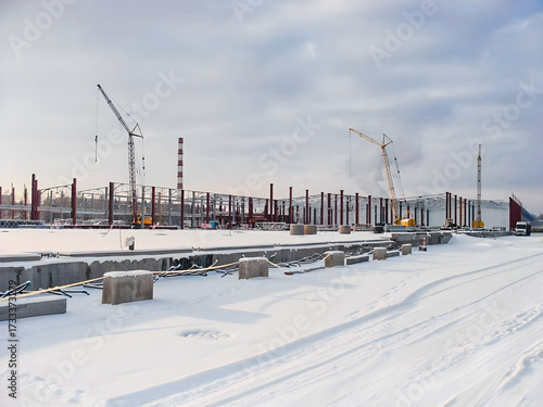 Construction site in winter with cranes and snow