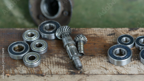 Close-up of metal ball bearings and machine gears on a wooden workbench. Mechanical parts and industrial tools for repair, engineering, and maintenance concepts.