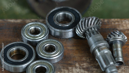 Close-up of metal ball bearings and machine gears on a wooden workbench. Mechanical parts and industrial tools for repair, engineering, and maintenance concepts.