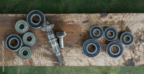 Close-up of metal ball bearings and machine gears on a wooden workbench. Mechanical parts and industrial tools for repair, engineering, and maintenance concepts.