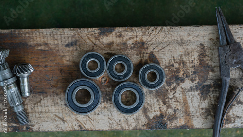 Close-up of metal ball bearings and machine gears on a wooden workbench. Mechanical parts and industrial tools for repair, engineering, and maintenance concepts.